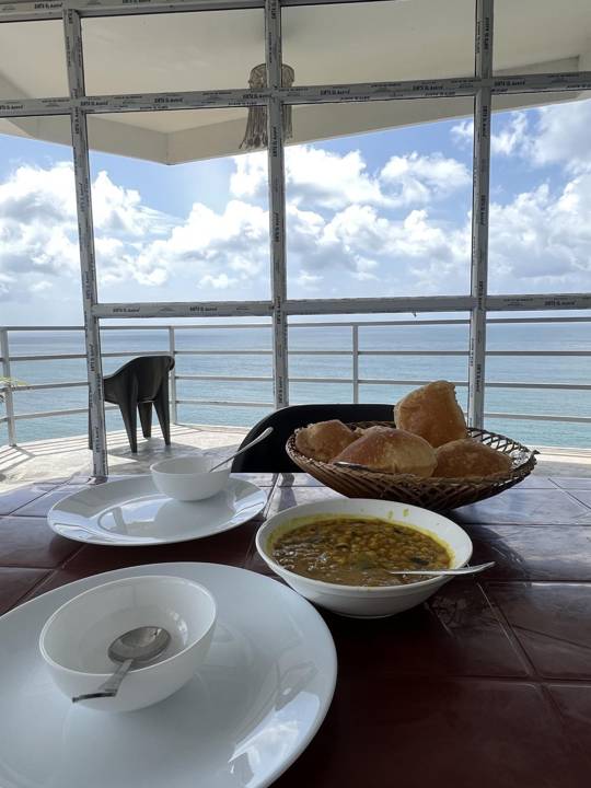 Breakfast of puri and dal on a table overlooking the sea